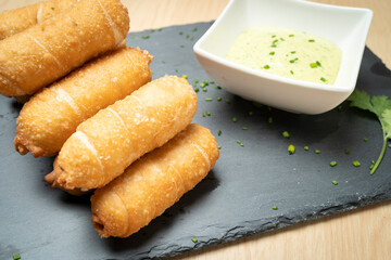 Delicious tequenos served with guasacaca sauce, a traditional venezuelan dish, ready to be enjoyed