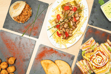 Delicious venezuelan cuisine including arepas, tequenos, meat with french fries, and a club sandwich, served on a wooden table