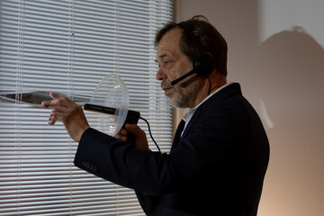 A private detective in the midst of a stakeout. Serious look, directional microphone and headset