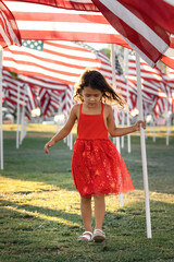 Child portrait of little girl standing with American flag on a Memorial Day, USA