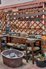 Traditional Andean basalt grinding stones displayed on wooden shelves, showcasing various shapes and sizes, with rustic ambiance and natural textures in an outdoor setting