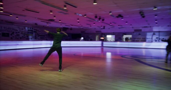 Steady cam movement with young man doing amazing roller skate tricks in front of friends under disco ball lights