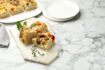 Pieces of delicious focaccia on white marble table. Space for text