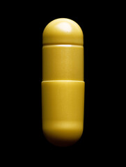 Yellow medicine capsule isolated on black background for health, wellness, and pharmaceutical needs