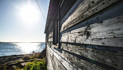 Weathered seaside shack, peeling paint and ocean view with bright sunlight