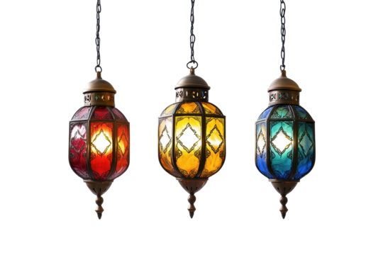 Three ornate, hanging lanterns in red, amber, and teal stained glass, illuminated from within against a black background