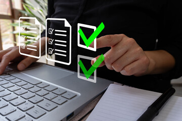 A person using a laptop computer with a green check mark icon on the screen and a document file, signifying quality control in business.