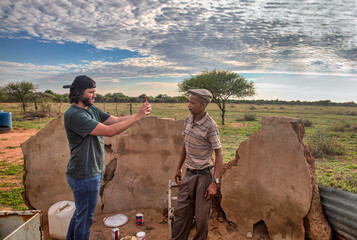 volunteer social worker at a NGO charity worker taking pictures of a village african man in front...