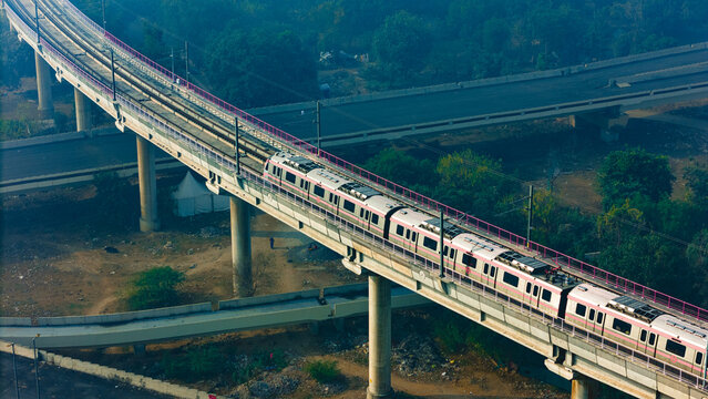 Top down view of The Delhi Metro is running on the tracks towards the Blue Line and Pink Line. Delhi Metro train. Cinematic drone shot of Metro rail in delhi.