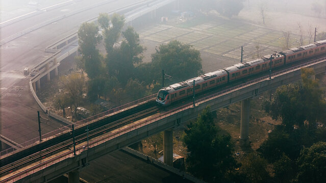Top down view of The Delhi Metro is running on the tracks towards the Blue Line and Pink Line. Delhi Metro train. Cinematic drone shot of Metro rail in delhi.