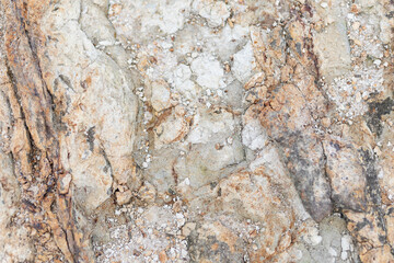 Rough, natural stone texture with earthy tones, perfect for rustic backgrounds and architectural design elements.
