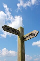 A wooden signpost points in opposite directions with the labels "Old Way" and "New Way