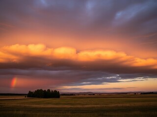 Dramatic sunset sky over golden fields rainbow