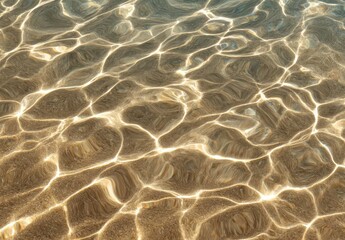 Sunlit shallow water reveals a sandy seabed through shimmering, rippling surface patterns