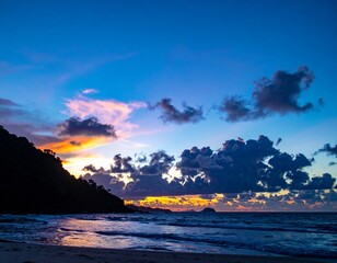 Dramatic Sunset Over Ocean with Silhouetted Mountain and Clouds.