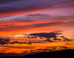 Fototapeta premium Fiery Sunset Over Silhouetted Mountains with Dramatic Cloud Form