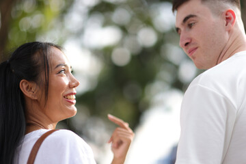 Happy young couple holding hands and smiling happily. Two young tourists happily walk hand in hand in a tourist area in a city in Thailand.