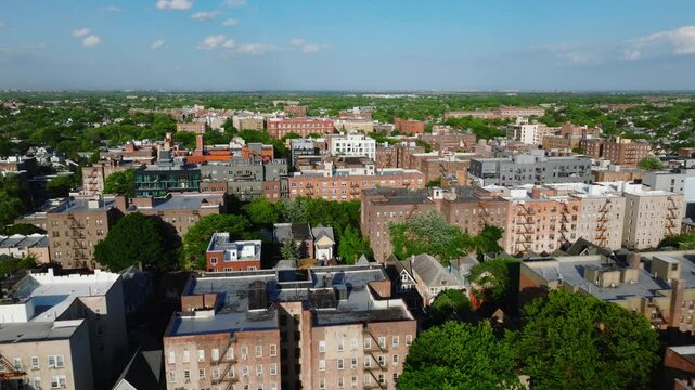 Aerial view of a residential neighborhood in Brooklyn, New York City, captured on a clear spring day. The image features mid-rise apartment buildings, tree-lined blocks, and dense housing patterns ext
