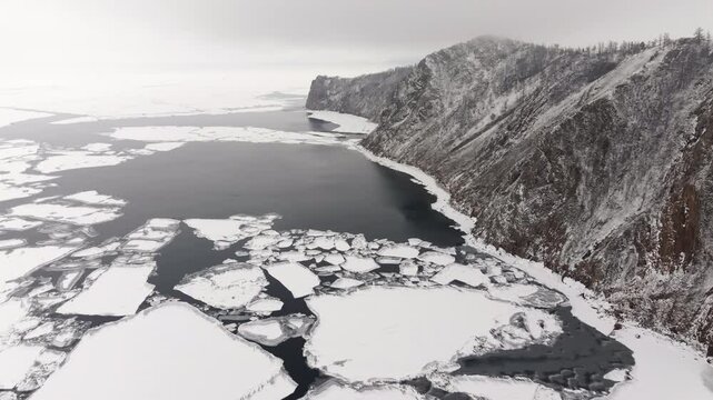 Aerial landscape view over sea ice floes, covered in snow, at overcast