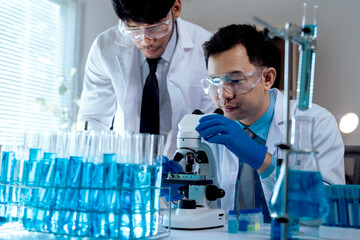Two scientists conducting experiments in a lab, examining samples under microscope and analyzing...