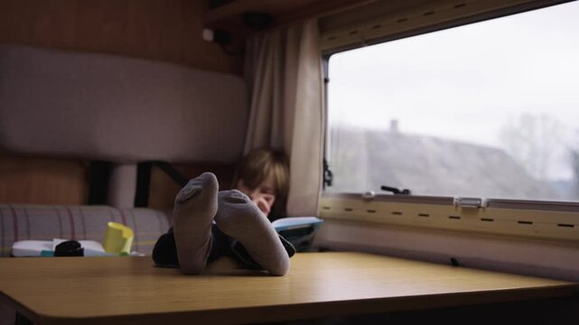 A casual scene shows a child reclining with feet up on a table inside a cozy RV cabin.