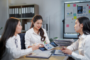 Asian businesswomen discussing company strategy during a meeting in a modern office, examining...