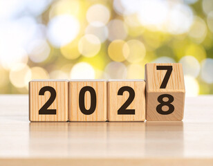 New Year Goals 2028. Flipping numbers 2027 to 2028 on a wooden block cube on a light bokeh