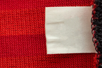 Blank white laundry care clothes label on red shirt fabric texture background
