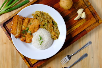a plate of chicken katsu rice with potato curry and a glass of iced tea