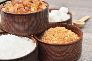 Brown sugar in wooden bowl with Belgian Brown Rock Beet Sugar background. Sugar type are fructose, glucose, lactose. Over consumption can be weight gain, type 2 iabetes and heart disese.