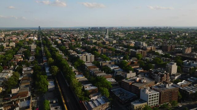 Aerial view of a residential neighborhood in Brooklyn, New York City, captured on a clear spring day. The image features mid-rise apartment buildings, tree-lined blocks, and dense housing patterns ext