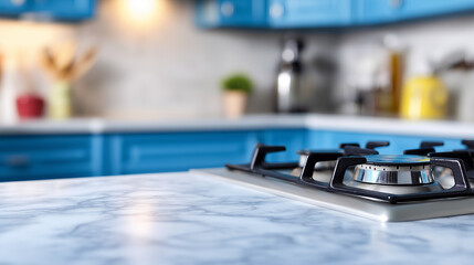 Obraz premium Modern kitchen with a marble countertop and built-in gas stove, blue cabinets and soft lighting in the background. 