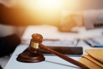 Lawyer shaking hands with a client making about documents, contracts, agreements, cooperation agreements with a female client at the lawyer's desk and a hammer at the table.