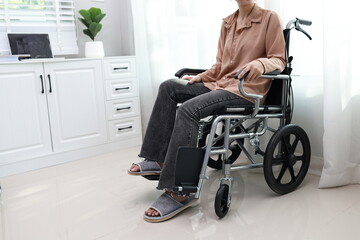 An elderly man sits in a wheelchair indoors, smiling with joy as a caring female nurse offers...