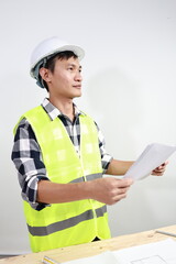 Fototapeta premium A young African American engineer wearing a hard hat reviews blueprints and discusses a construction project with a colleague at a modern industrial site. 