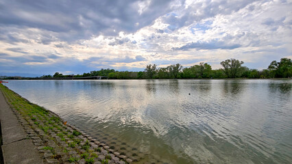 Rowing canal in Plovdiv, Bulgaria – calm water reflecting the sky, bordered by trees and greenery. Peaceful atmosphere, ideal for sports and walks.