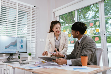 Business professionals analyzing investment graphs and financial charts on laptops during a strategic meeting in a modern office environment.