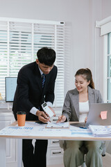 Businesswoman and colleagues in formal office setting discussing financial charts and strategy, collaborating on investment analysis using laptops and documents.