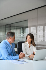 Naklejka na ściany i meble Two busy professional business man and woman executives team using laptop working on computer having conversation on financial project in office. Bank manager consulting client at meeting. Vertical
