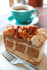 Slice of Delectable Mixed Nuts Coffee Cake with Blurry Hot Coffee in the backdrop