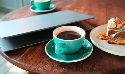 Cup of coffee and fork scooping candied nut with laptop in the backdrop