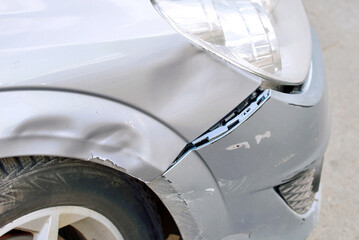 Gray car front bumper showing visible dent and scratch damage with paint chipping after low speed...
