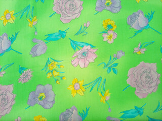 Floral pattern features a variety of flowers, including roses, daffodils, and other blossoms in shades of pink, purple, and yellow, scattered across a bright green background