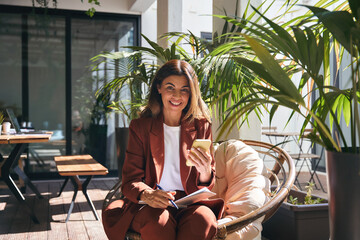 Happy smiling elegant mature older business woman holding cellphone using mobile cell phone looking...