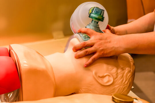 Healthcare worker practicing artificial respiration on CPR dummy with ambu bag. Essential emergency training for rescue breathing, first aid, and cardiac arrest intervention techniques.