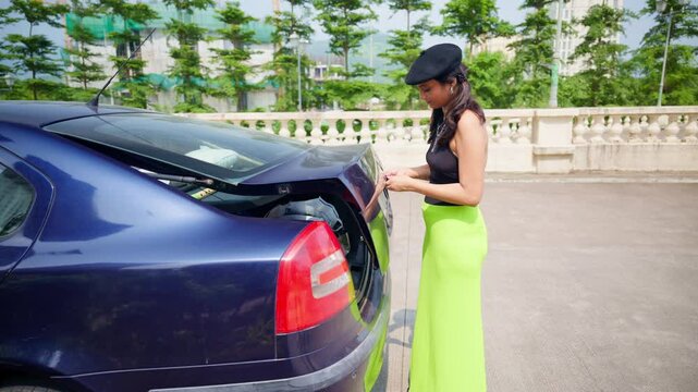 Cap wearing girl opens car dicky near holiday spot