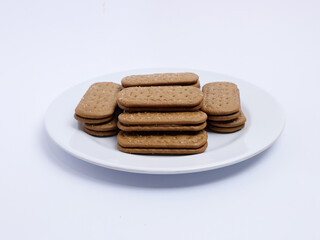 Stack of rectangular biscuits with sugar topping neatly arranged on a white plate, isolated on a white background