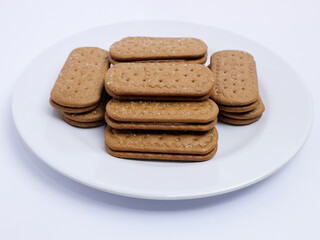 Stack of rectangular biscuits with sugar topping neatly arranged on a white plate, isolated on a white background
