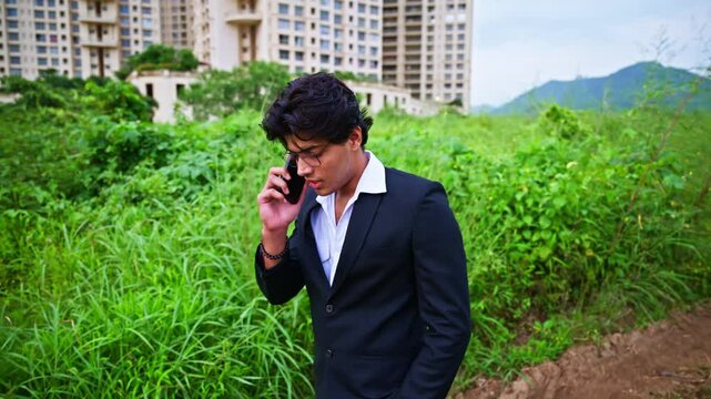 Corporate male moves down rugged path as he talks on phone