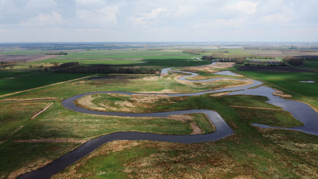 Meandering river nature landscape aerial drone photo grass land and body of water stream curves and corners. Dutch natural scene.
